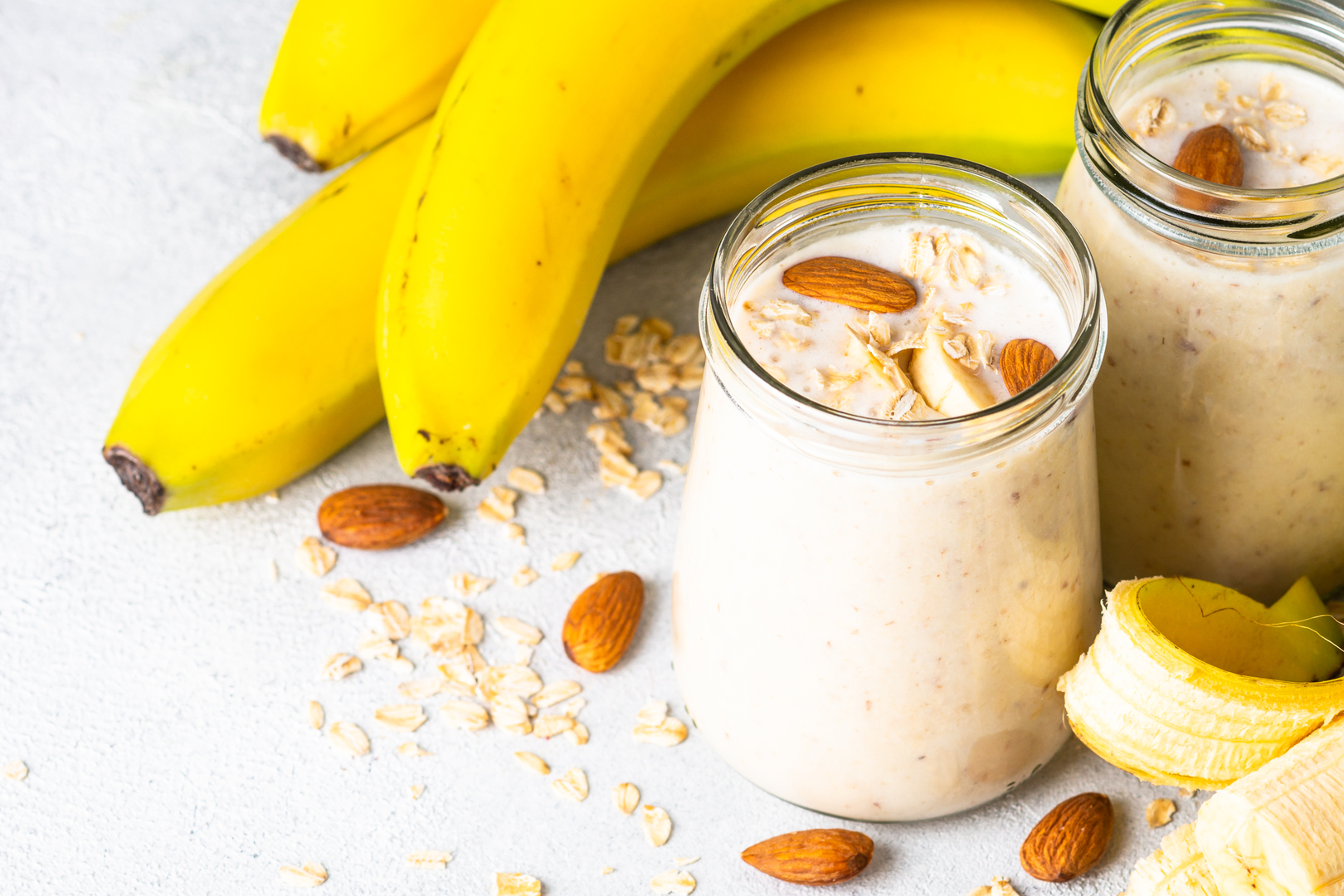 Almond banana smoothie with oat flakes in glass jars.