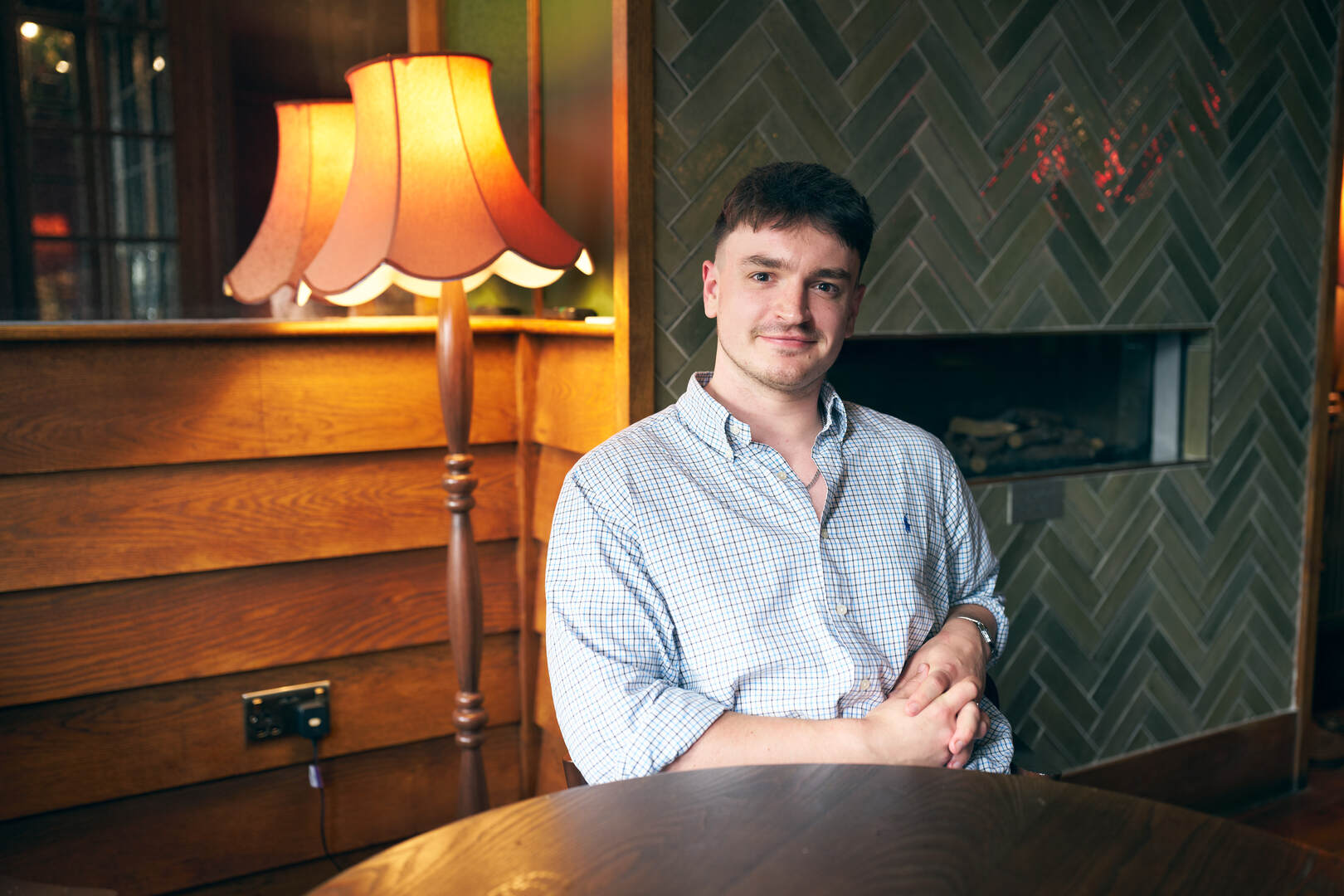 A young man sits at a table in a restaurant.